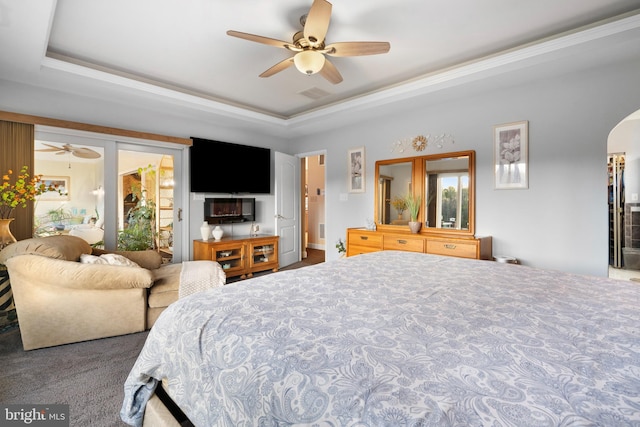 bedroom featuring visible vents, a ceiling fan, a tray ceiling, and arched walkways