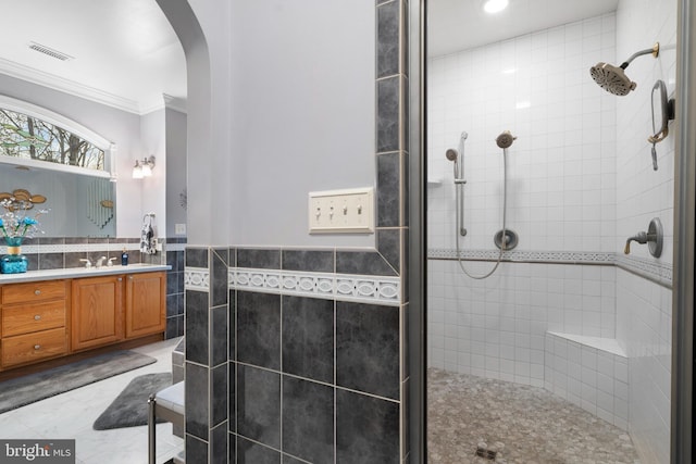 bathroom with tile walls, visible vents, a shower stall, and ornamental molding