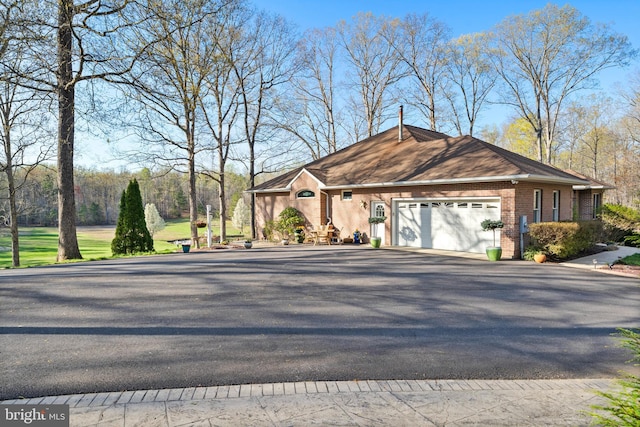 single story home featuring an attached garage, driveway, and brick siding