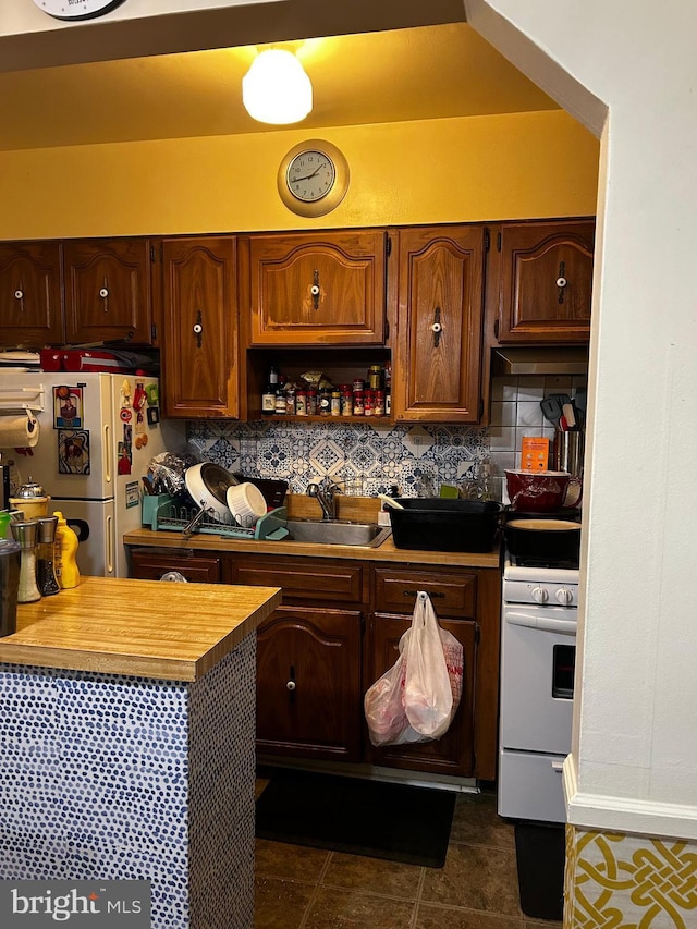 2834 Edgecombe Cir S, Baltimore, MD 21215 - kitchen featuring white stove, freestanding refrigerator, tasteful backsplash, and dark tile patterned flooring