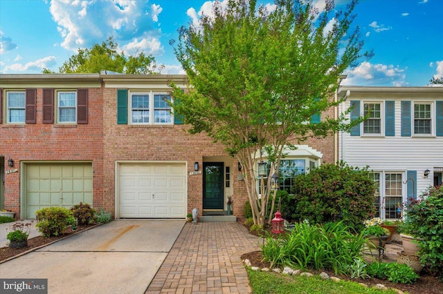 view of property with driveway, a garage, and brick siding