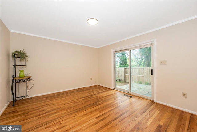 spare room with light wood finished floors, crown molding, and baseboards