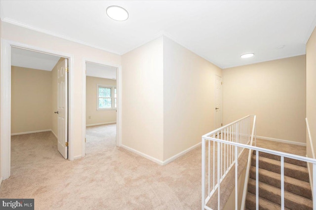 hall featuring carpet flooring, ornamental molding, and baseboards