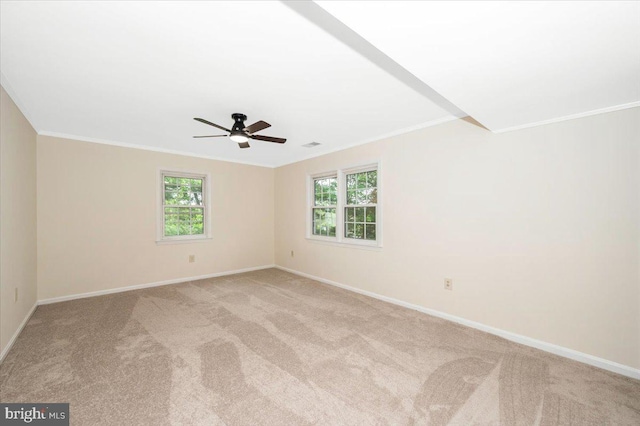 empty room featuring crown molding, light colored carpet, baseboards, and healthy amount of natural light