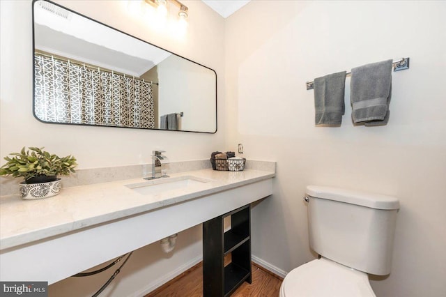 full bath featuring toilet, vanity, wood finished floors, and baseboards
