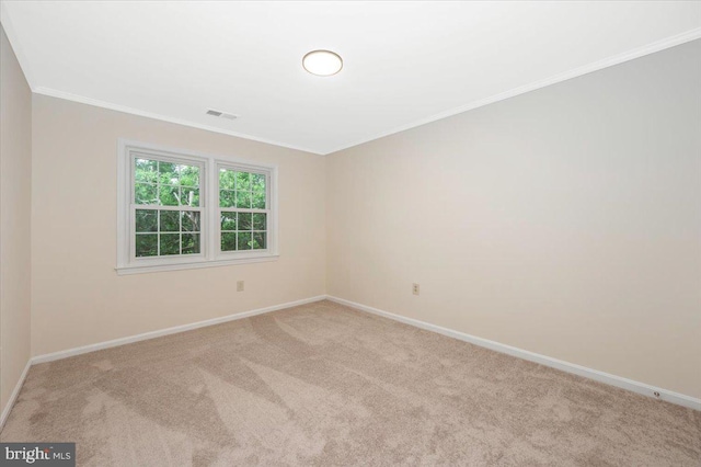 carpeted empty room featuring baseboards and crown molding