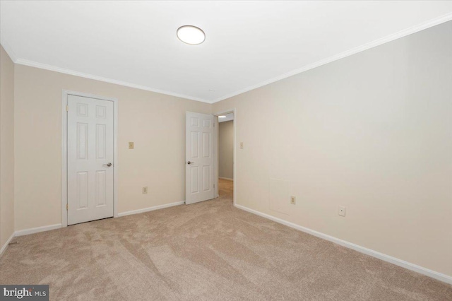 unfurnished bedroom featuring light colored carpet, ornamental molding, and baseboards