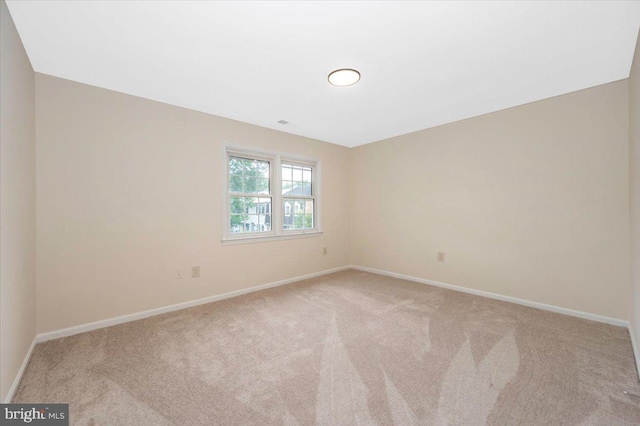 carpeted spare room featuring baseboards