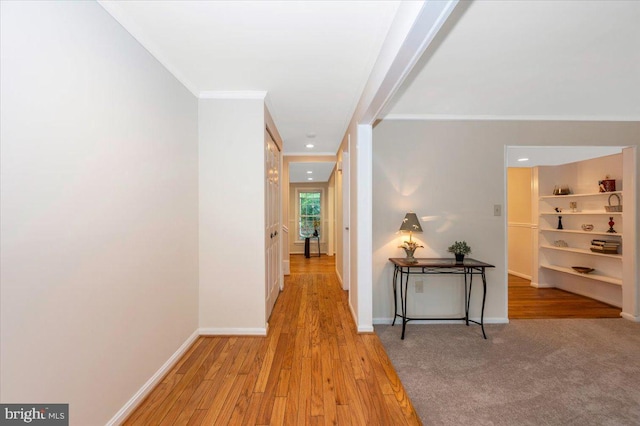 hallway with ornamental molding, wood finished floors, and baseboards