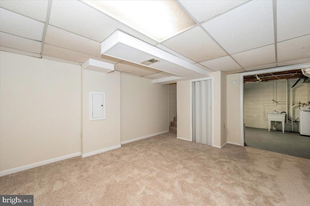 finished basement with carpet, a paneled ceiling, baseboards, and washer / clothes dryer