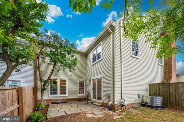 rear view of house featuring central air condition unit, a fenced backyard, and a patio area