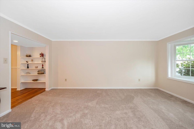 unfurnished room featuring crown molding, carpet, baseboards, and built in features