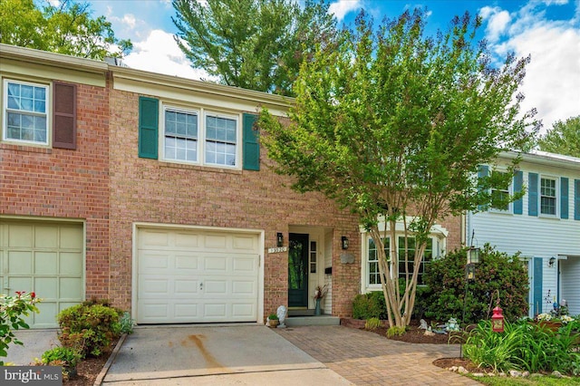 townhome / multi-family property with driveway, a garage, and brick siding