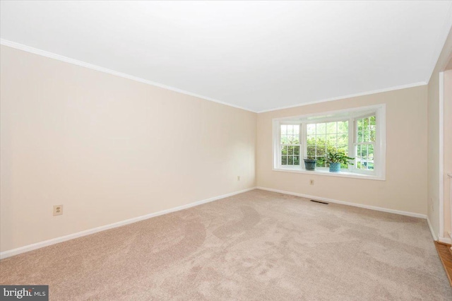 spare room with baseboards, ornamental molding, and light carpet