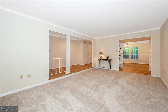 spare room with a chandelier, ornamental molding, carpet flooring, and baseboards