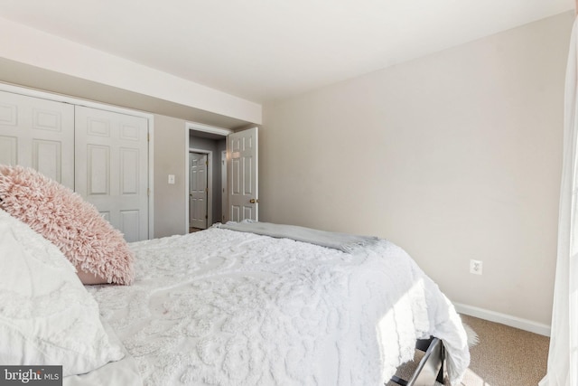 bedroom with baseboards, carpet floors, and a closet