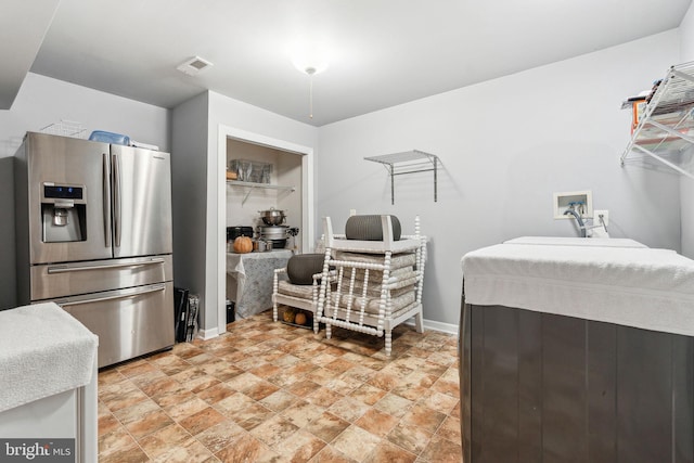 interior space featuring stone finish floor, stainless steel fridge with ice dispenser, visible vents, and baseboards