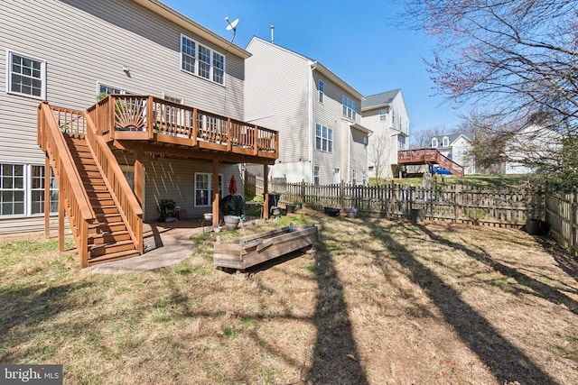 back of property with a yard, a deck, a fenced backyard, and stairs