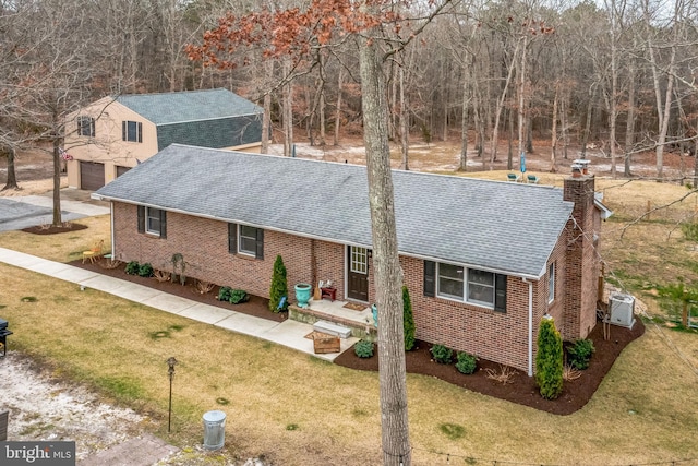 view of front of house featuring brick siding, a chimney, a front lawn, and a shingled roof