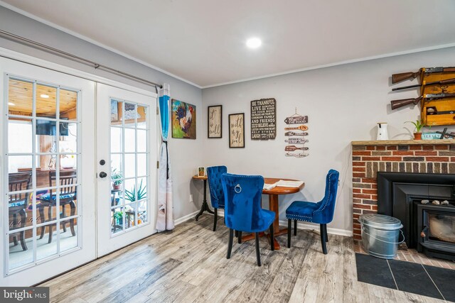 dining area featuring wood finished floors, baseboards, a wood stove, french doors, and crown molding