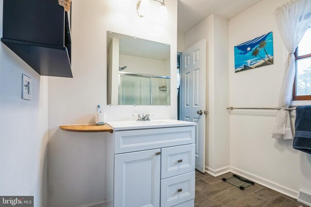 bathroom with an enclosed shower, visible vents, wood tiled floor, baseboards, and vanity