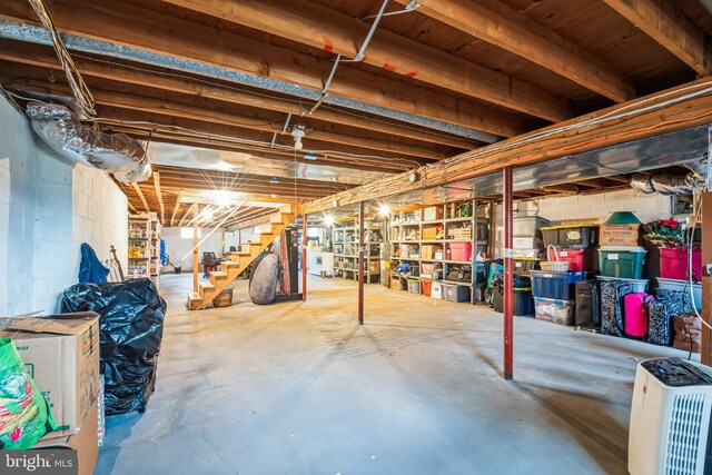 unfinished basement with stairway and concrete block wall
