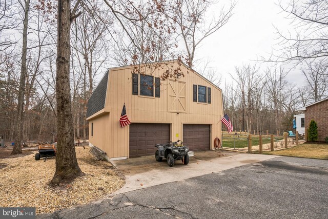 exterior space with aphalt driveway, a detached garage, and fence