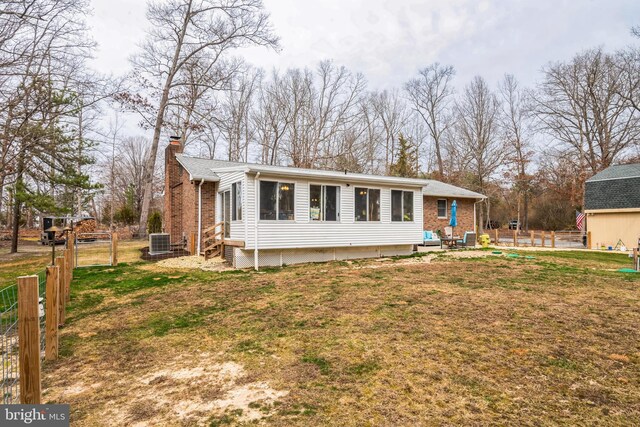 view of front of house featuring central AC unit, fence, a chimney, entry steps, and a front lawn
