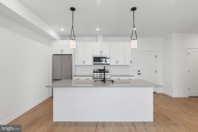 kitchen with stainless steel appliances, light wood-style floors, an island with sink, and white cabinets