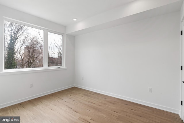 spare room with a wealth of natural light, baseboards, and light wood-style floors