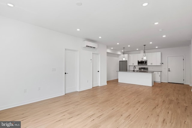 unfurnished living room with light wood-style flooring, a sink, a wall unit AC, recessed lighting, and baseboards