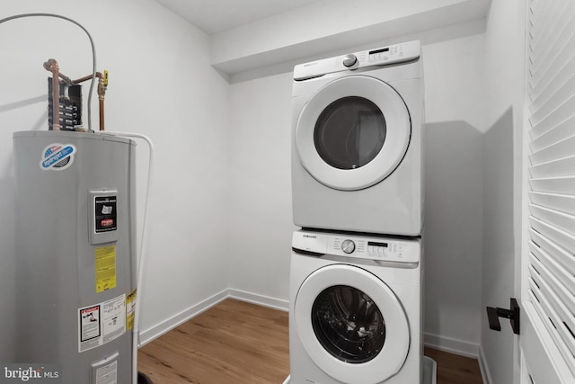 laundry area featuring stacked washer and clothes dryer, wood finished floors, water heater, and laundry area