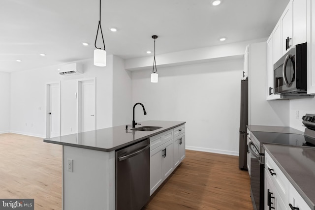 kitchen featuring a sink, stainless steel appliances, light wood-style floors, a wall mounted air conditioner, and dark countertops