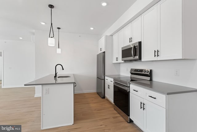 kitchen with dark countertops, appliances with stainless steel finishes, light wood-style floors, and a sink