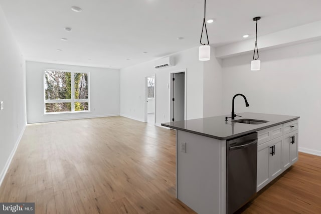 kitchen with light wood-style flooring, a sink, stainless steel dishwasher, dark countertops, and open floor plan