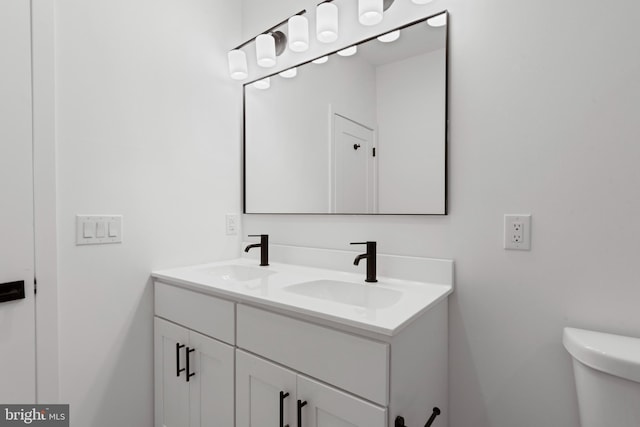 bathroom with double vanity, toilet, and a sink