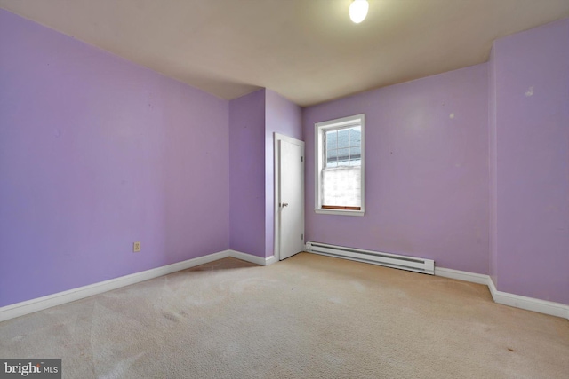 spare room featuring a baseboard heating unit, carpet flooring, and baseboards