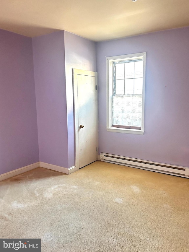 carpeted spare room featuring baseboard heating and baseboards