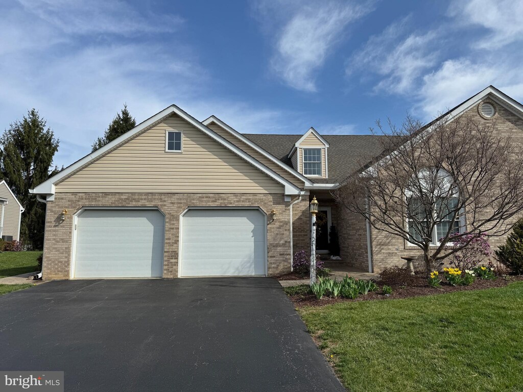 view of front facade featuring a front yard, brick siding, a garage, and aphalt driveway