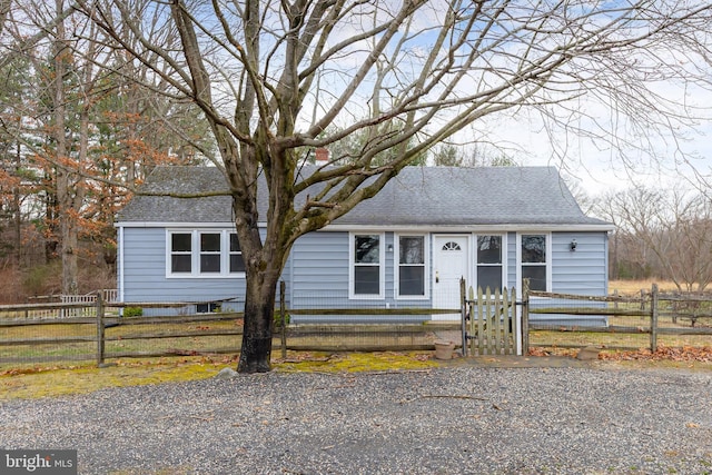 view of front of property with a fenced front yard, roof with shingles, and a gate