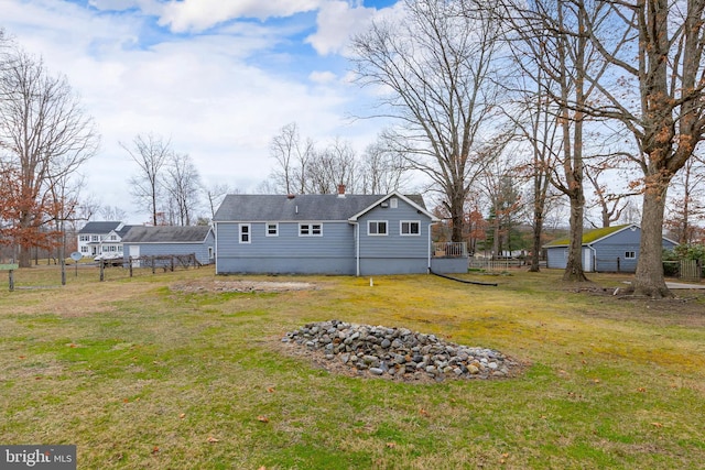 back of property featuring a lawn and fence