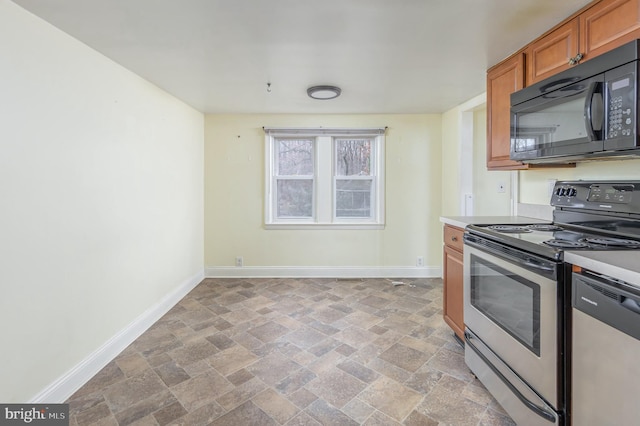 kitchen featuring stone finish flooring, baseboards, appliances with stainless steel finishes, and light countertops