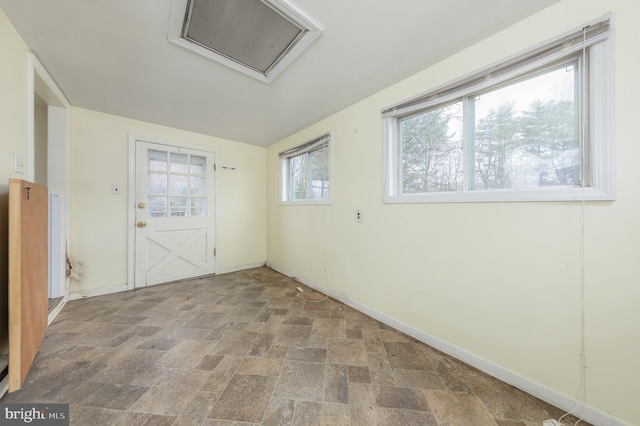 spare room with attic access, baseboards, and stone finish flooring