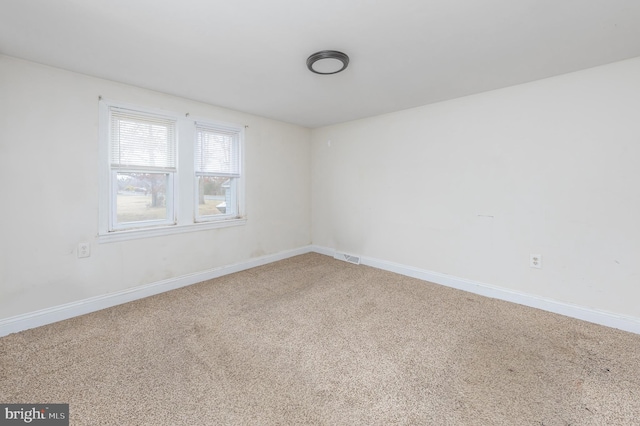 carpeted spare room with visible vents and baseboards