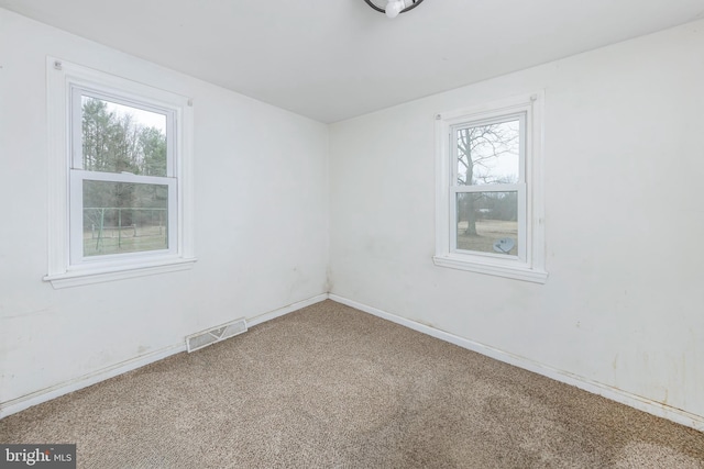 carpeted empty room featuring visible vents and baseboards