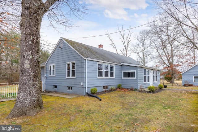 view of front of home with a shingled roof, a front lawn, fence, and a chimney