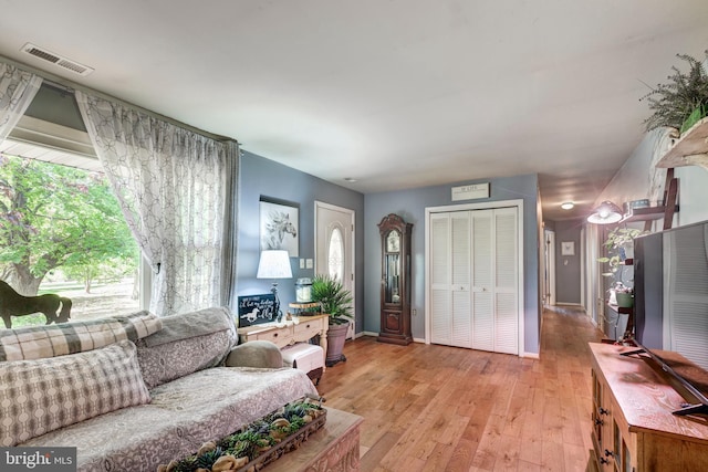 living room with visible vents, light wood-style flooring, and baseboards