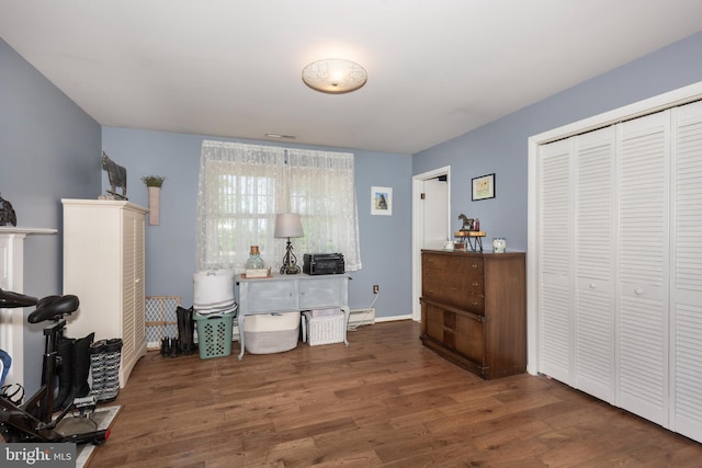 bedroom featuring a closet, wood finished floors, and baseboard heating