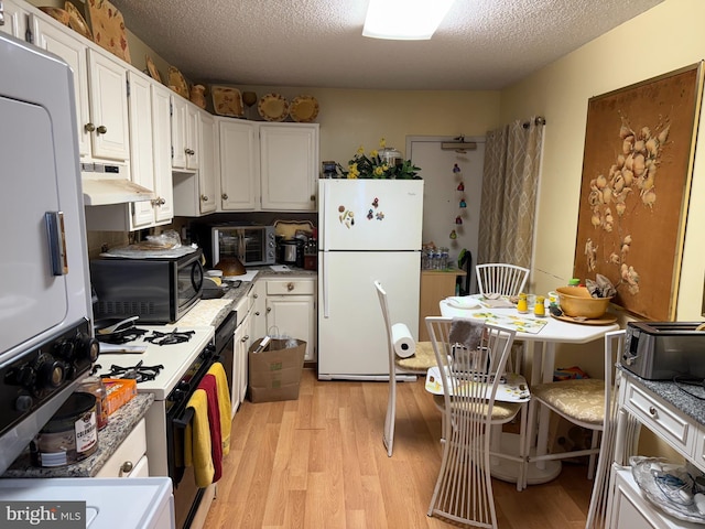 kitchen with a textured ceiling, light wood-type flooring, under cabinet range hood, white appliances, and white cabinetry