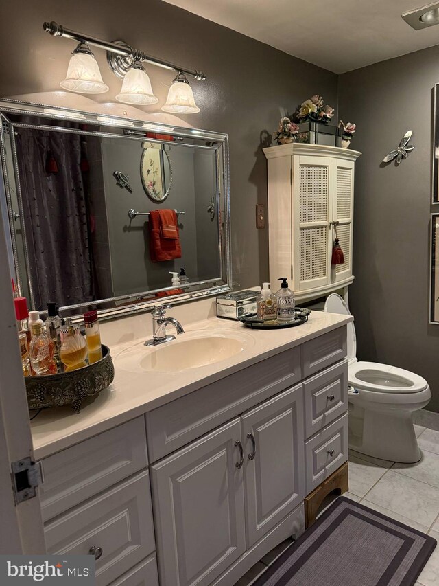 bathroom with toilet, tile patterned flooring, and vanity